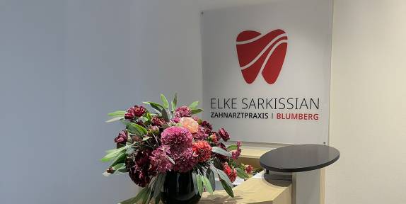 Anmeldung mit Blumenstrauß und Logo auf Glas im Hintergrund