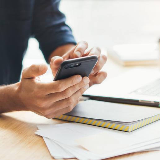 Person am Arbeitsplatz läd am Handy Dokumente herunter